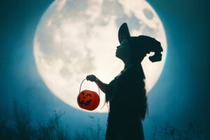 Picture of girl in front of the moon holding a Halloween lantern