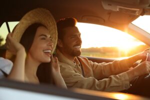 Picture of a man and woman driving in a car with the windows down